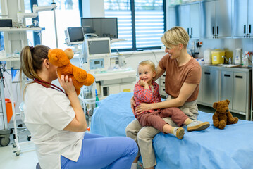Female pediatrician comforting little boy with teddy bear.