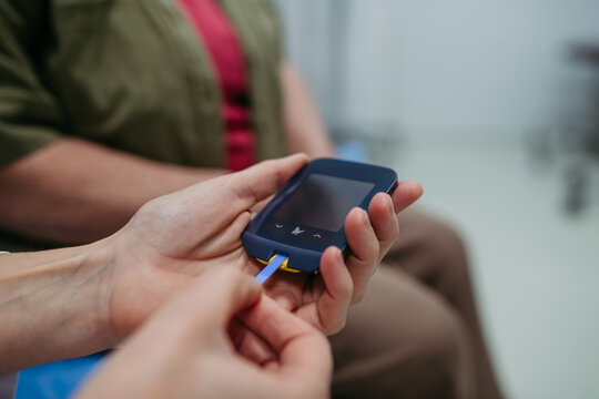 Close-up of hands using blood glucose meter during medical exam. - Powered by Adobe