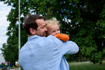 Portrait of dad hugging little son, enjoying time together