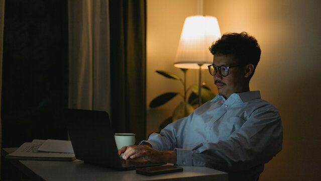 Asian man working at night on his laptop