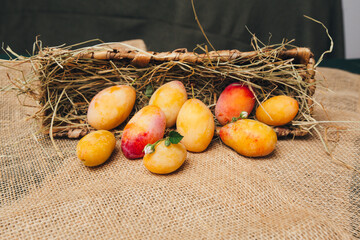 Still life with yellow plums in a basket, located on a light wooden surface, minimalism and naturalness.
