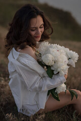 Happy woman holding a bouquet of flowers at sunset on a top above the sea