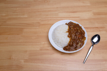 top view of homemade Japanese curry rice with beef carrot beans and onion in white dish on wood table