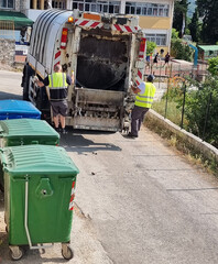 garbage truck workers collecting rubbish cans
