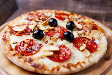 Pizza with salami and mozzarella cheese. Wooden background. Soft focus. Close up.	