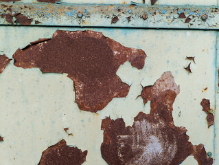 A rusty metal surface with peeling paint on it