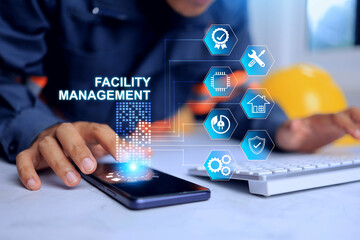 Facility management concept with engineer working in office desktop to manage and monitoring facility works infrastructure system in smart city via smart phone hologram