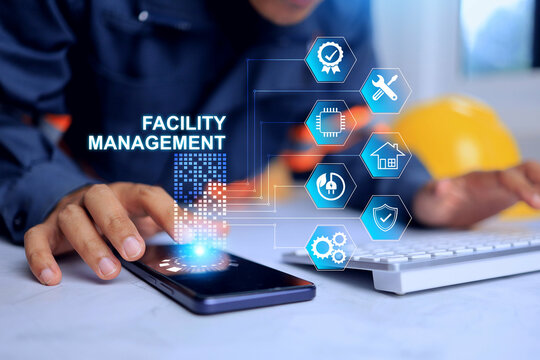 Facility management concept with engineer working in office desktop to manage and monitoring facility works infrastructure system in smart city via smart phone hologram