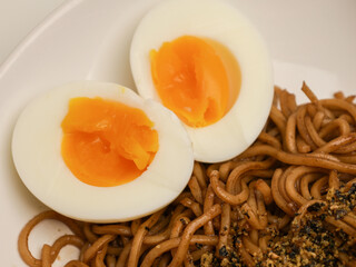 Soba noodles or fried noodles and boiled egg on white plate