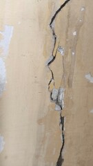Long Vertical Crack on Old Beige Wall with Peeling Surface and Clear Signs of Structural Damage –...