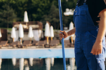 Pool cleaner holding cleaning net by the poolside, getting ready for work