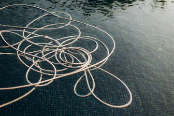White floating hose in swimming pool reflecting sunlight