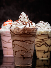 Chocolate milkshake served in a clear glass on a dark background. Isolated drink