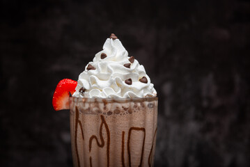 Chocolate milkshake served in a tall glass on a dark background. Isolated drink