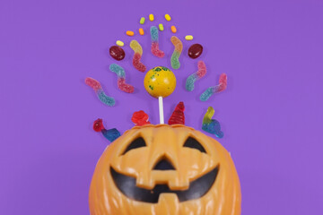 Fototapeta premium Halloween concept. Top view photo of pumpkin basket with candies purple background