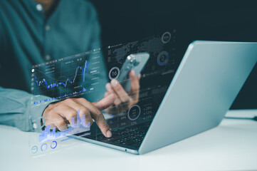 A person interacts with a laptop and smartphone, analyzing digital financial charts and data visualizations in a tech-driven workspace.