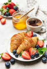 Delicious breakfast with croissants, coffee, berries and honey enjoying morning meal