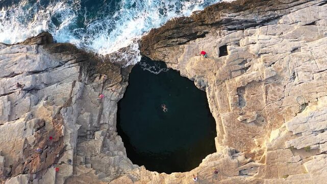  Stunning aerial top down slow motion view of a woman swimming in the Giola natural sea pool, lagoon. Thassos island, Greece