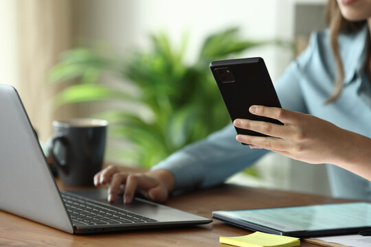 Businesswoman hands using multiple devices on a wooden table