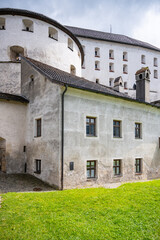 Kufstein Fortress stands proudly in Tyrol, Austria, showcasing its impressive architecture against a backdrop of green lawns and cloudy skies, inviting visitors to explore its rich history.