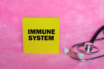 Immune System writing concept on sticky note isolated on pink background. stethoscope as decoration.