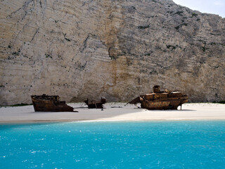The shipwreck on Navagio Beach captured frontally, set against majestic limestone cliffs under a...