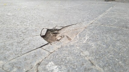 Cracked grey marble stone texture with dark fissures and detailed rough surface. Large crack in a tiled floor, in a urban slate road surface, suggesting structural damage.  Perfect for backgrounds.