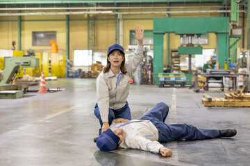 工場で倒れた作業員を発見し助けを呼ぶ女性作業員