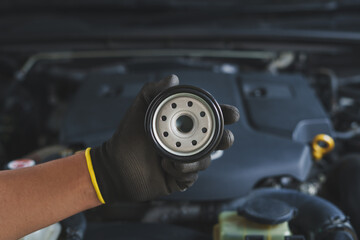 Mechanic holds up a new, clean oil filter, ready for installation during a routine car maintenance...