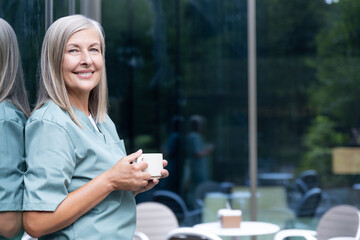 Mature caucasian female doctor having coffee and looking relaxed