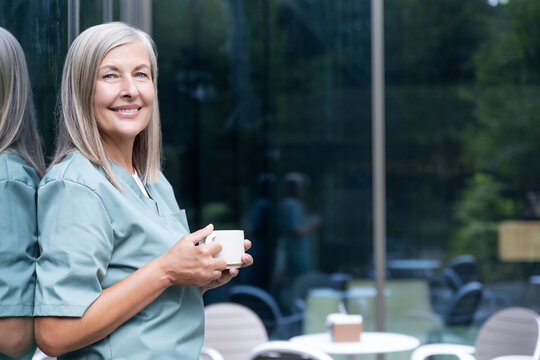 Mature caucasian female doctor having coffee and looking relaxed - Powered by Adobe