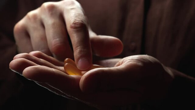 hand with healthy capsules and omega3 vitamins.
Fish oil in the hands of a man.
Capsules with liquid inside.
Omega 3 for improved well-being.
Healthy food and vitamins