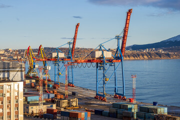 View of the port cranes and piers of the seaport. Maritime transport and port infrastructure in the Russian Far East. Nagaev Bay, Sea of Okhotsk. Magadan, Magadan Region, Russia.