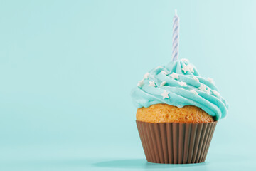 Festive cupcake topped with swirled frosting and a lit candle