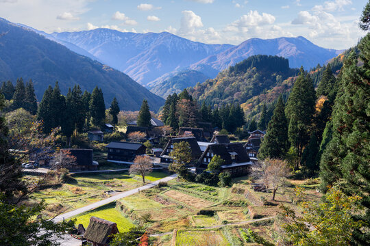 Traditional gassho zukuri houses in Ainokura village, Japan surrounded by autumn forests and mountain ridges, captured from a high viewpoint