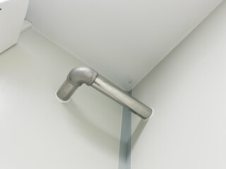 Stainless steel plumbing pipe system installed in clean white interior corner, showcasing modern industrial design, functionality. Ideal for engineering, construction, plumbing system concepts