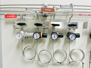 Industrial gas control panel with pressure gauges and regulators for hydrogen, nitrogen, helium, and zero air supply in laboratory. engineering system for monitoring and controlling gas distribution