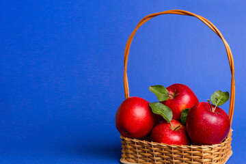 Ripe garden apple fruits with leaves in basket on wooden table. Top view flat lay with copy space