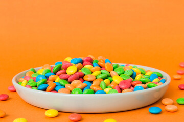 Multicolored candies in a bowl on a colored background. birthday and holiday concept. Top view with copy space