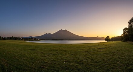 a grassy field with a lake and mountains in the background