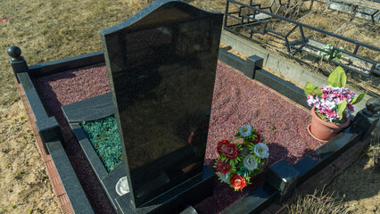 A granite gravestone with a plate and an overturned empty shot glass symbolizes remembrance of deceased relatives. A tribute to family traditions, loss, and honoring loved ones at the cemetery.