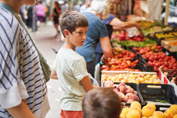 Boy shopping for fruit at a busy outdoor market