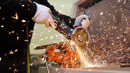 Metalworker using angle grinder with flying sparks. Close-up of a worker cutting metal with an angle grinder, producing bright flying sparks in a workshop setting.