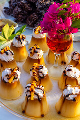 Portioned caramel cream with whipped cream and berry sauce