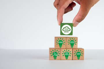 Hand building a pyramid with ESG, Net Zero, and ISO 14001,CO2 reduction symbol.,Concept for sustainability strategy,climate action,enviromental,business.,white background with copyspace.