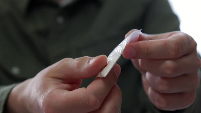 The man takes out a bag of drugs from his pocket.
A man holds a bag of heroin in his hands.
Drug addicted man and a package of illegal drugs.
cocaine trade