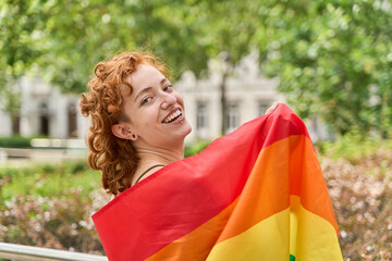 Happy activist showing rainbow flag at gay pride parade