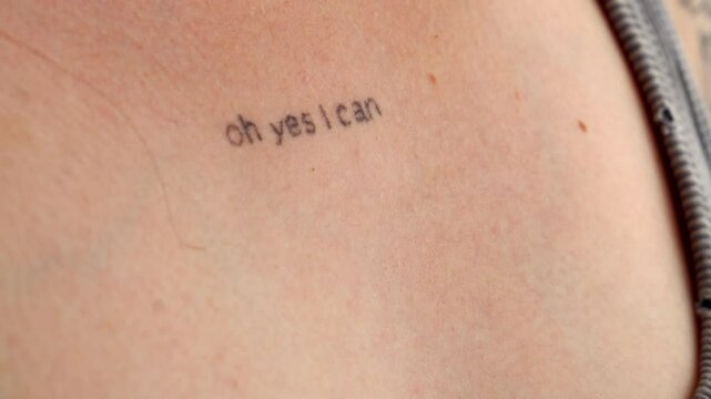 A graphic design on the body of a young girl.
Tattoo on a woman's chest.
The inscription on the chest is OH YES I CAN close-up.
Stylish and modern tattoo in a minimalist style