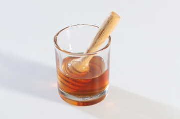 Wooden honey dipper resting in glass of honey