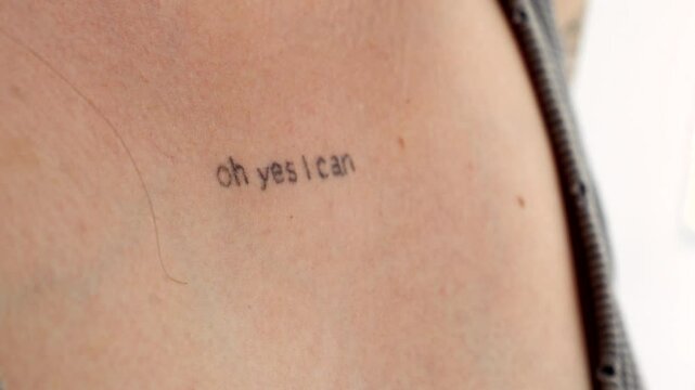 A graphic design on the body of a young girl.
Tattoo on a woman's chest.
The inscription on the chest is OH YES I CAN close-up.
Stylish and modern tattoo in a minimalist style